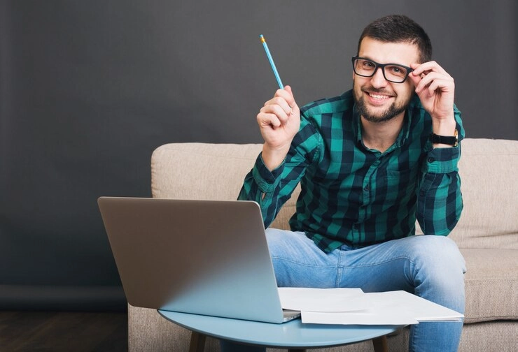 a person having pen in hand and laptop in the table and pointing his value