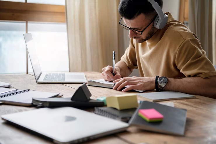 a person having many books on the table and working properly and having headphones